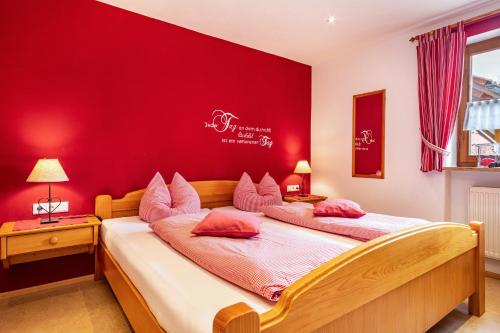 two beds in a room with a red wall at Ferienwohnung Hahn in Weißensberg