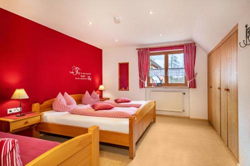 a bedroom with red walls and a bed with pink pillows at Ferienwohnung Hahn in Weißensberg