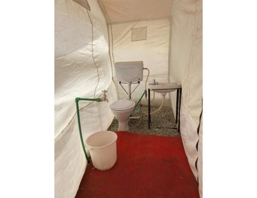 a tent with a toilet and a table in it at Dorje Camps Sarchu, Manali in Manāli