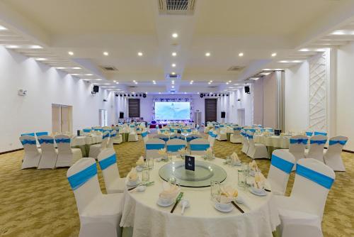 a banquet hall with white tables and chairs and a screen at Ben Tre Riverside Resort in Ben Tre