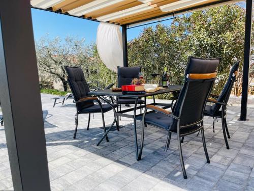 ein Esstisch und Stühle auf einer Terrasse in der Unterkunft Holiday House Tesser with Pool in Galižana