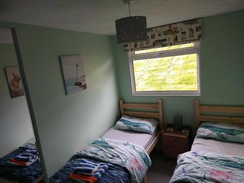 a bedroom with two beds and a mirror and a window at 238 Norton Park, Dartmouth 2 bed holiday home with free parking in Dartmouth