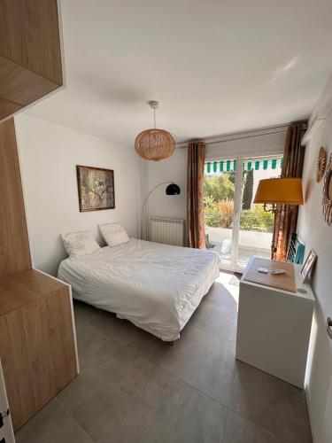 1 dormitorio con cama blanca y ventana en La Garde d'Antoine - Appartement centre ville en La Garde