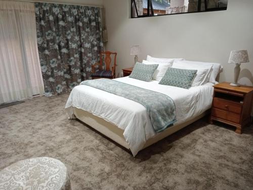1 dormitorio con 1 cama con sábanas y almohadas blancas en Drakenzicht Mountain Cottage, en Winterton