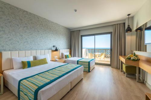 ein Hotelzimmer mit einem Bett und einem Schreibtisch in der Unterkunft Calido Maris Hotel Ultra All Inclusive in Kızılot