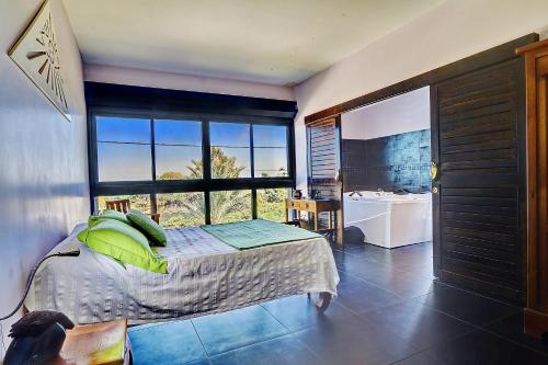 - une chambre avec un lit et une grande fenêtre dans l'établissement La Villa des Mainates - Jacuzzi et vue mer, à Le Tampon