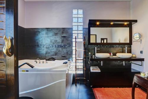 La salle de bains est pourvue d'un grand miroir et d'un lavabo. dans l'établissement La Villa des Mainates - Jacuzzi et vue mer, à Le Tampon