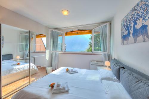 a bedroom with a bed and a large window at Apartments Gelsomino, Orchidea and Magnolia in Castagnola