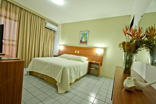 a hotel room with a bed and a vase of flowers at Petrolina Palace Hotel in Petrolina