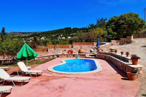a swimming pool with two chairs and an umbrella at Diamond Villas in Gavalochori