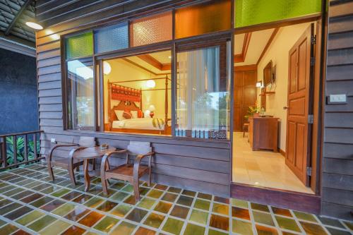 a room with a balcony with a bed and a table and chairs at มนต์เมืองเชียงใหม่ รีสอร์ต Monmuang Chiangmai Resort in Hang Dong
