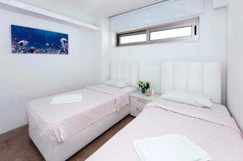 2 camas en un dormitorio con paredes blancas y ventana en Apartment Marisol - Beachfront, en Protaras