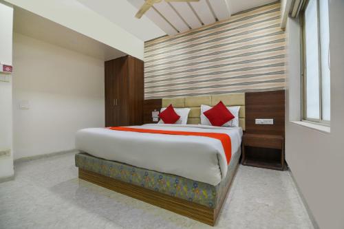 a bedroom with a large bed with red pillows at Sunshine Inn Near Pune Railway Station in Pune