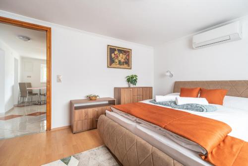 a bedroom with a large bed with an orange blanket at Topáz Apartmanházak Keszthely in Keszthely