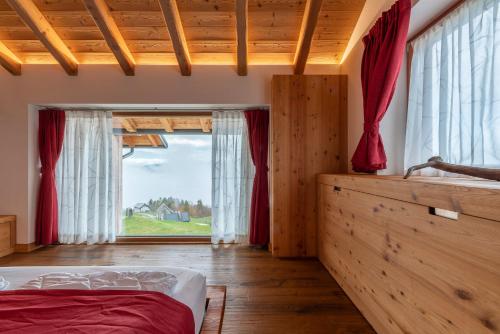 a bedroom with a bed and a large window at Casera Degnona in Chies dʼAlpago