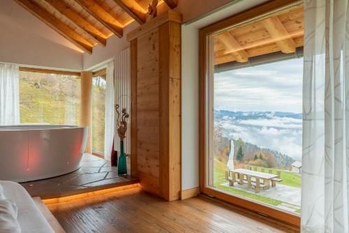 a bathroom with a tub and a large window at Casera Degnona in Chies dʼAlpago