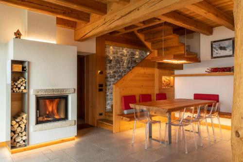 a dining room with a fireplace and a table and chairs at Casera Degnona in Chies dʼAlpago