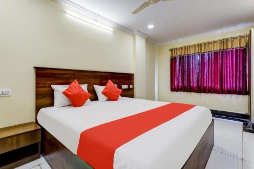 a bedroom with a large bed with red pillows at Collection O Hotel Srinivasa Residency in Tirupati
