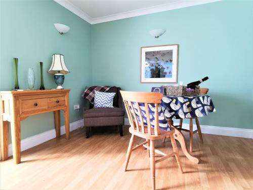 comedor con paredes azules, mesa y silla en Romantic Cottage with Private Hot Tub, en Llanfyrnach