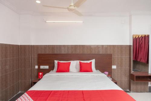 a bedroom with a large bed with red pillows at Capital O Hotel Srinivasa Residency in Tirupati