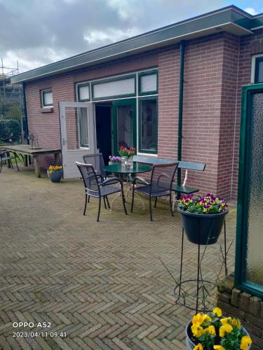 a patio with a table and chairs and flowers at De Grindweg in Holten