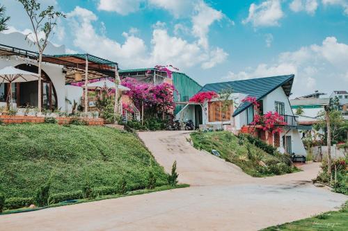 uma casa com flores cor-de-rosa ao lado de uma estrada em Laca homestay em Gia Nghĩa