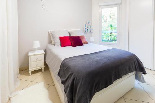 Un dormitorio blanco con una cama grande con almohadas rojas en PALATINO - MONACO - 2 PIECES - Parking, en Beausoleil