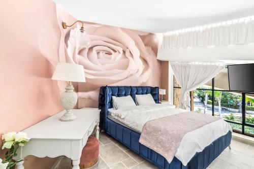 a bedroom with a blue bed and a pink rose wall at Tzel Hailan - צל האילן in ‘Omer