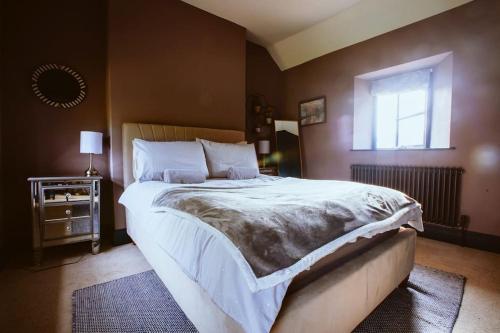 a bedroom with a large bed and a window at Beautiful 5 bedroom house with hot tub & fire pit in Abergavenny