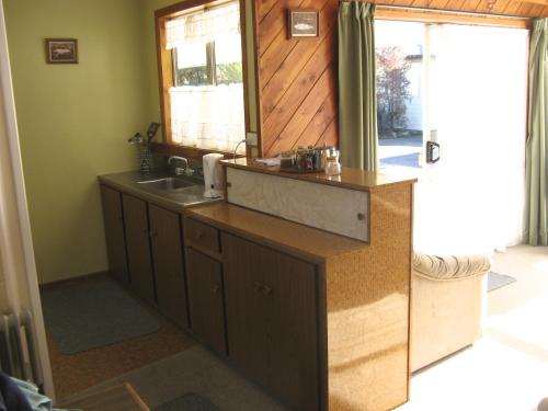 a kitchen with a sink and a mirror at Tongariro River Motel in Turangi