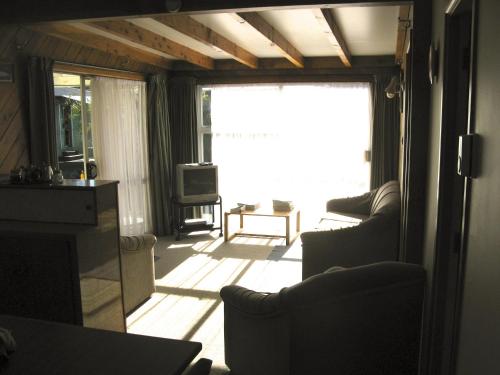 a living room with couches and a large window at Tongariro River Motel in Turangi