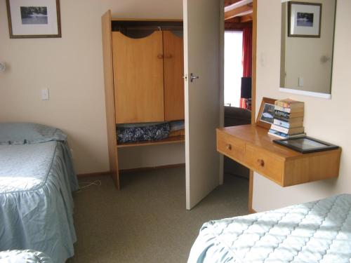 a bedroom with a bed and a desk with a mirror at Tongariro River Motel in Turangi