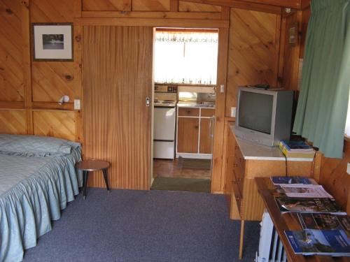 a small bedroom with a bed and a television at Tongariro River Motel in Turangi