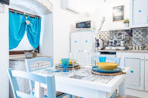 cocina con mesa blanca y sillas azules en Vico di Ostuni Apartments by Rentbeat, en Ostuni