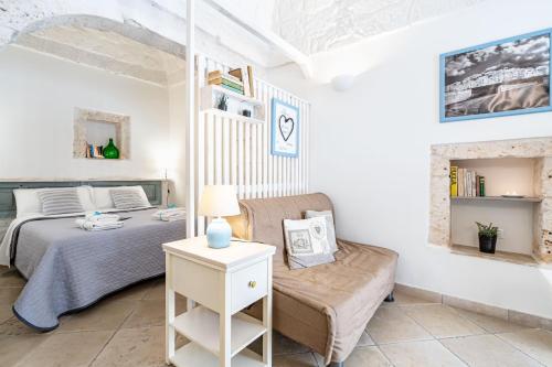 a bedroom with a bed and a couch at Vico di Ostuni Apartments by Rentbeat in Ostuni