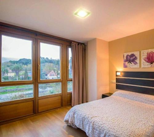 a bedroom with a bed and a large window at Apartamentos Camparina in Llanes