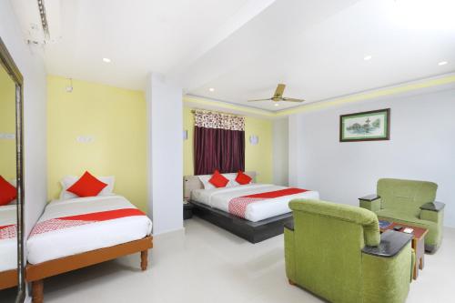una habitación de hotel con 2 camas y una silla en Hotel Sai Golden Rooms, en Tirupati