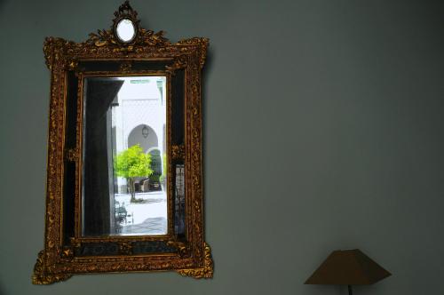 an ornate mirror hanging on a wall next to a lamp at Palais Faraj Suites & Spa in Fès