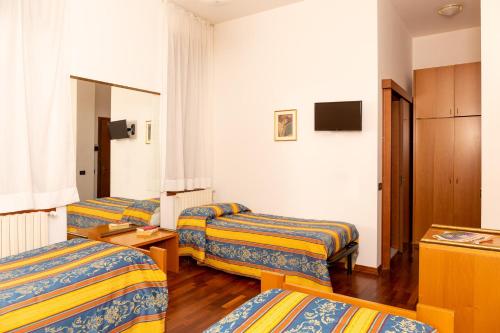 a hotel room with three beds and a television at Albergo Sacro Monte Varese in Varese