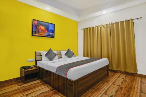 a bedroom with a bed with yellow walls and wooden floors at Townhouse Hotel Pine Tree in Indore