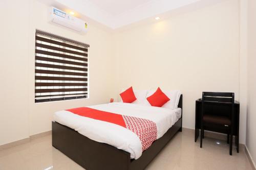 a bedroom with a bed with red pillows and a window at Hotel Better Inn in Ernakulam