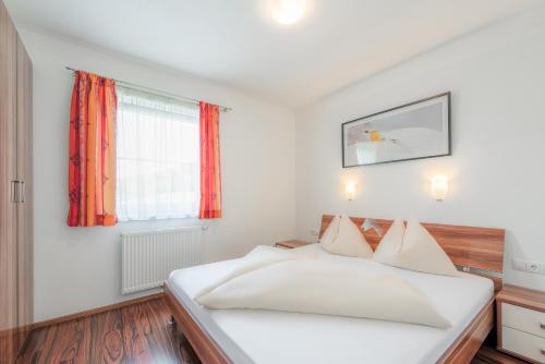 1 dormitorio con cama blanca y ventana en Alpenjuwel Appartements en Flachau