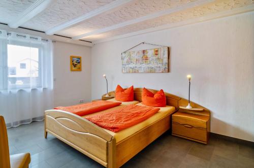 1 dormitorio con cama con sábanas de color naranja y ventana en Ferienwohnung Lindau en Sipplingen