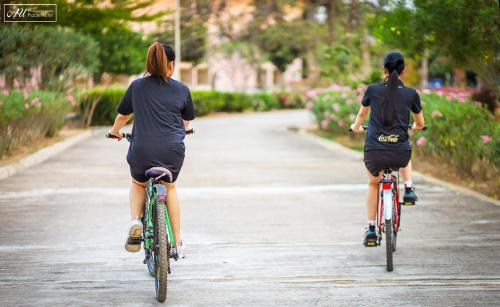 two people riding bikes down a road at AU Place Hotel in Loei