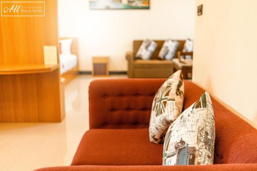 an orange couch with pillows on it in a living room at AU Place Hotel in Loei