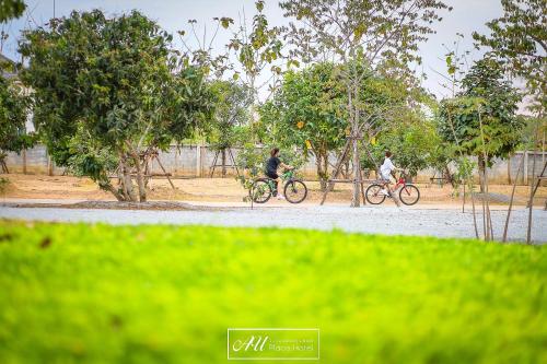 two people riding bikes on a dirt road at AU Place Hotel in Loei