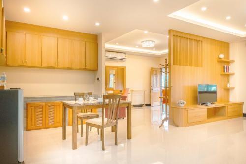 a kitchen with wooden cabinets and a table and chairs at AU Place Hotel in Loei