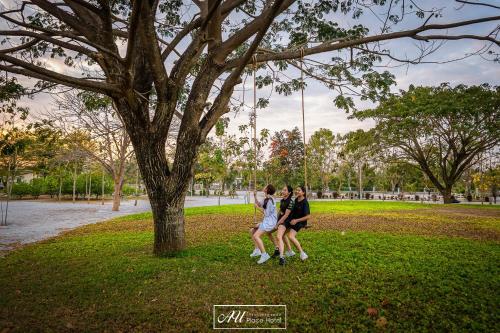 two people sitting on a tree in a park at AU Place Hotel in Loei