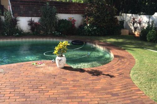 um vaso de flores sentado num caminho de tijolos ao lado de uma piscina em Sagelands for business travel & family getaways em Durban