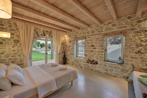 1 dormitorio con 1 cama grande en una pared de piedra en villa Armonia -Pitsidia, Matala, Kalamaki, en Pitsidia